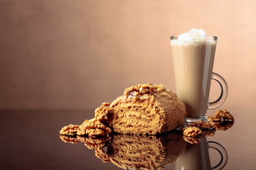 Walnut cake and coffee latte with cream on a reflective background.