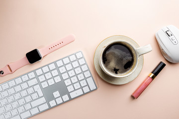 Flat lay or top view office table desk. Workspace with blank, keyboard, pen, green plant succulent, and coffee cup on pink background.