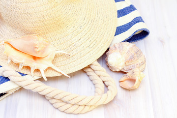 Seashells, a beach bag and a straw hat on a wooden light background. Travel and vacation concept.