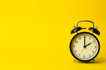 Time background concept. Vintage classic alarm clock on yellow empty background. Time management...