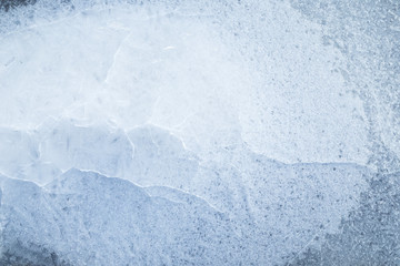 Close-up of cracked ice on a frozen lake in the winter, viewed from above. Abstract full frame background. Copy space, top view.