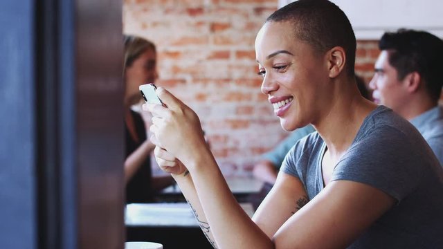 Woman using mobile phone sitting at table in coffee shop - shot in slow motion