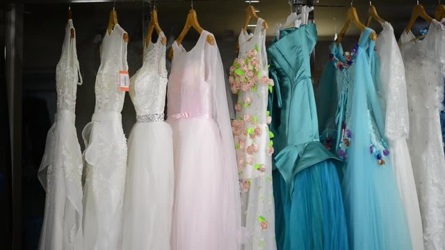 Pan shot of range of many colorful dresses for special occasion in shop