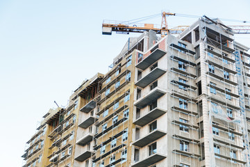 overpopulating the earth. view of a dwelling house under construction and a crane on background