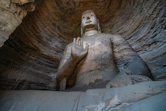Yungang Buddhist Grottoes. An ancient huge sitting buddha statue carved directly in the mountain rock. Datong, China