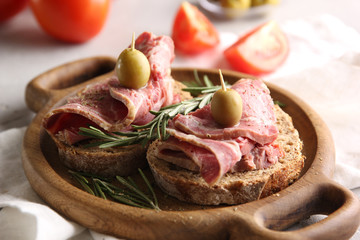 Lunch. Ham sandwiches on a wooden board. Olives, tomatoes and rosemary on a light background. Background image, copy space
