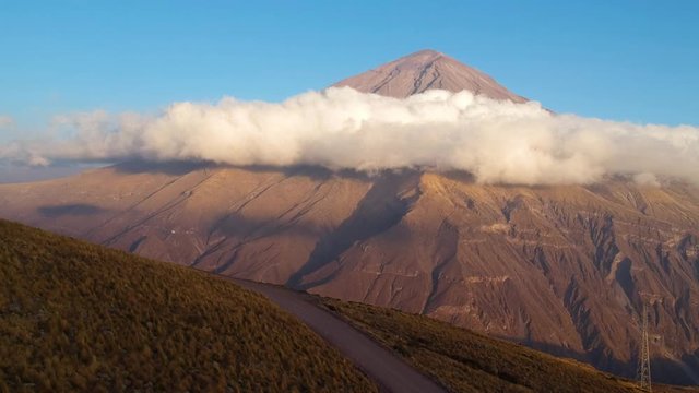 Peruvian Misti Volcano with clouds below its peak. Aerial rising.