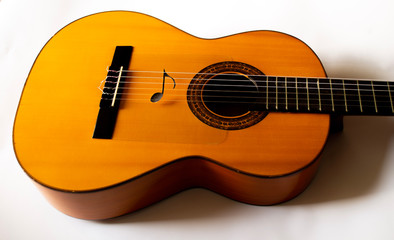 A single musical note on the strings of a Spanish acoustic guitar.