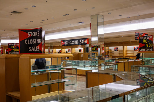 Sign For A Store Closing Sale On Top Of An Empty Jewelry Display Case With Empty Illuminated Shelves