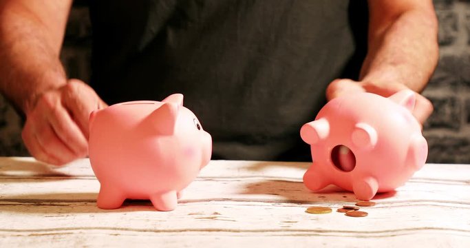 Emptying two piggy banks with unequal shares of money, financial concept
