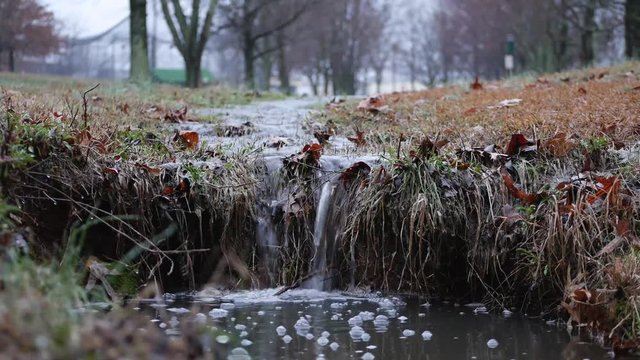 Man walking over stream of water flowing into creek