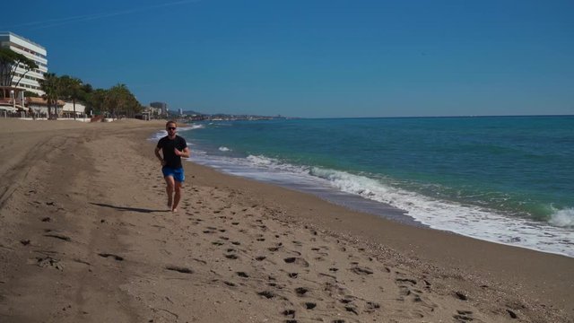 Caucasian man running along the beach seen ahead