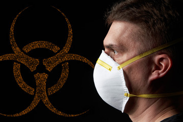 side view / profile of a young man wearing a protective mask in dark atmosphere - orange biohazard...