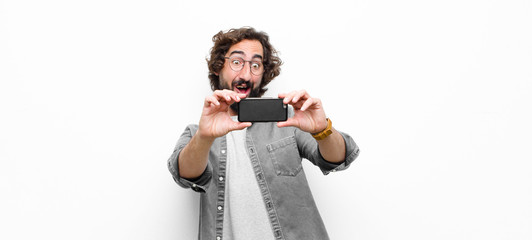 young crazy cool man using his smartphone against white wall