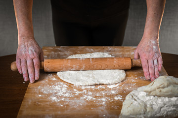 the cook rolls out the dough with a rolling pin. hands close up