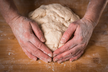 Making dough by female hands on wooden table background close up