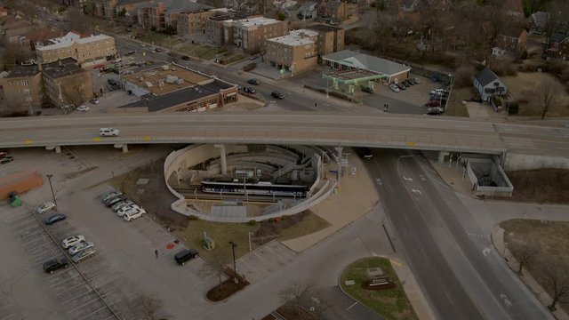 Aerial of train station at Forsyth in Clayton Missouri, tilt up as train leaves station.