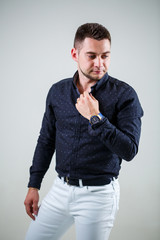 Young businessman guy in black shirt and white trousers on a white background