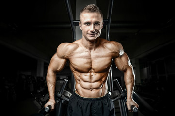 Bodybuilder strong man pumping up abs muscles