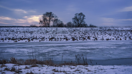 Winter landscape with frozen river and trees in the snow