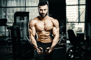 Muscular bodybuilder at cable crossovers fitness