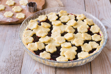 Blueberries jam pie decorated flower cookies on wooden table before baking