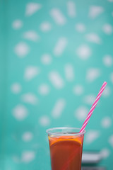 glass of juice with straw on blue background