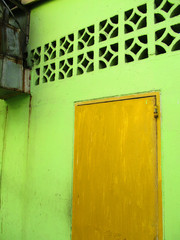 Unevenly painted door (yellow mustard) with a light lime green wall  behind