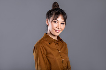 Portrait of a young beautiful asian female student woman in studio on gray.