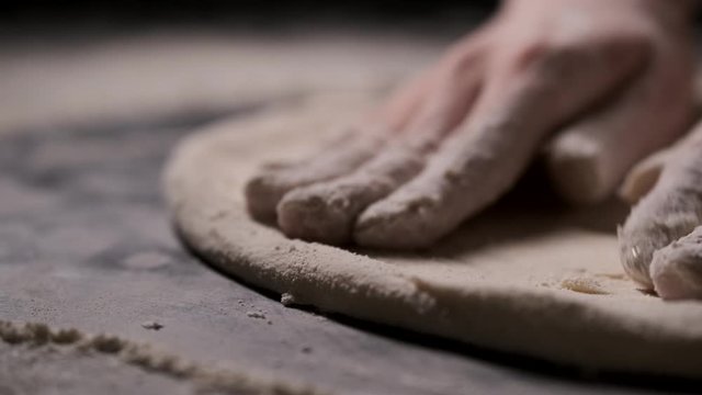 An experienced chef in a professional kitchen prepares the dough to make pizza . with flour. Process, stages of cooking pizza. juicy, mouth-watering pizza. the concept of nature, Italy, fast food