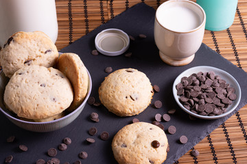 bol con galletas de chocolate pepitas leche en pizarra con vela leche tapón en esterilla en una...