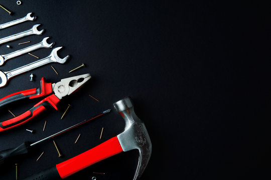 Construction tools for home renovation on black background. Red hammer, pliers, screwdriver, wrenches, screws. Maintenance, reparing concept. Place for text, flat lay.