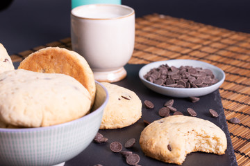 bol con galletas de chocolate pepitas leche en pizarra con vela leche tapón en esterilla en una botella