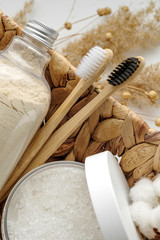 Fototapeta na wymiar Spa and wellness cosmetic products: body scrub, beech toothbrushes, sea bath salt, soap, wooden hair comb in a wicker basket. Natural beauty product, Skin care, body treatment concept.