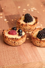 Healthy cereals muffins with berries and yellow cream on the wooden desk.