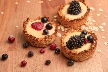 Healthy cereals muffins with berries and yellow cream on the wooden desk.