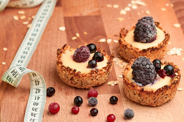 Healthy cereals muffins with berries and measuring tape on the wooden desk.