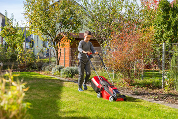 Boy cutting the grass with lawn mower