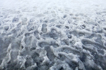 human footprints melted snow slush winter water gray background top view