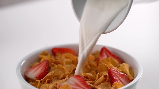 Pouring milk onto cereal with strawberries in slow motion