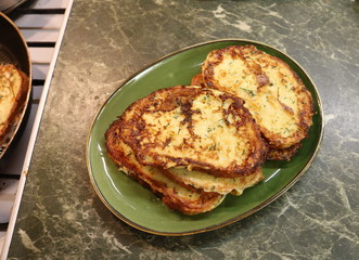 Delicious croutons of white bread with dill lie on a green oval plate on a green stone table next to the stove. 
