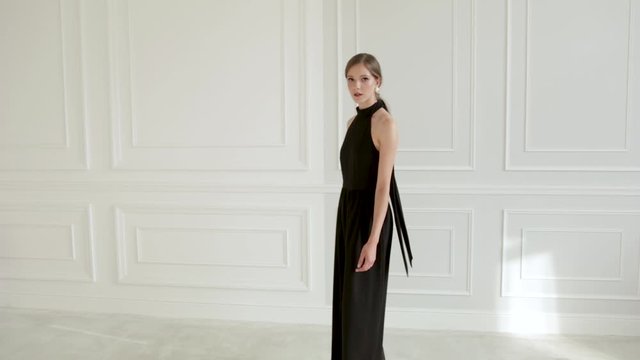 beautiful girl in black clothes walks in a white room