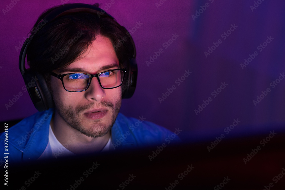 Poster gamer man using pc playing computer game indoor at night