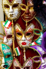 A portrait of a venetian carnival mask surrounded by other of the same mysterious masks in a shop. Ready to be bought and to hide your identity at a masked or costumed ball or maybe halloween.