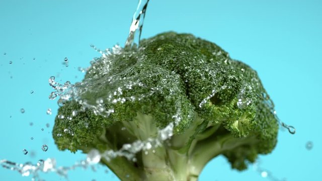 Water spinning off broccoli on blue background.  Shot in slow motion with Phantom Flex 4K camera.