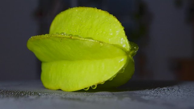 Side view ripe carambola fruit. Cross section. Light slowly rotating about averrhoa. Play of light and shadow. Dark background. Close-up. Macro. 4k