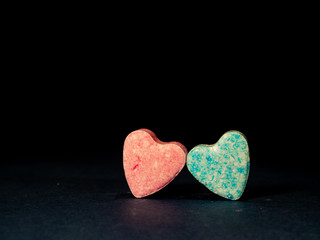 Two heart-shaped candies on the black background.