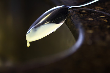 Obraz premium Balanced spoon in the kitchen sink to be used again later. Dripping condensed milk.