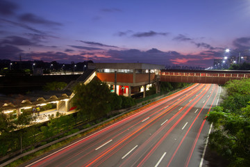 Fototapeta premium Sunset, the night in metropolis, train station and vehicles in transit. Sao Paulo city highway beside the river. Skyline, cars and traffic on the road at high speed.
