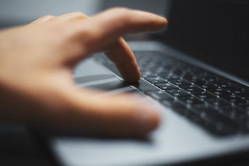 Close-up of male hand typing buttons of laptop keyboard.